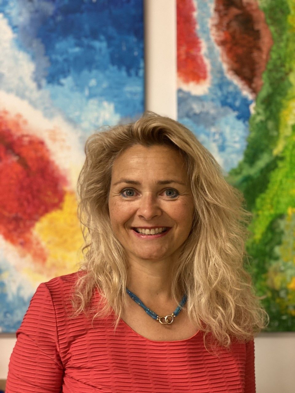 Dr. Claudia Mlynek-Luhr vor einem farbenfrohen Gemälde in ihrer Praxis