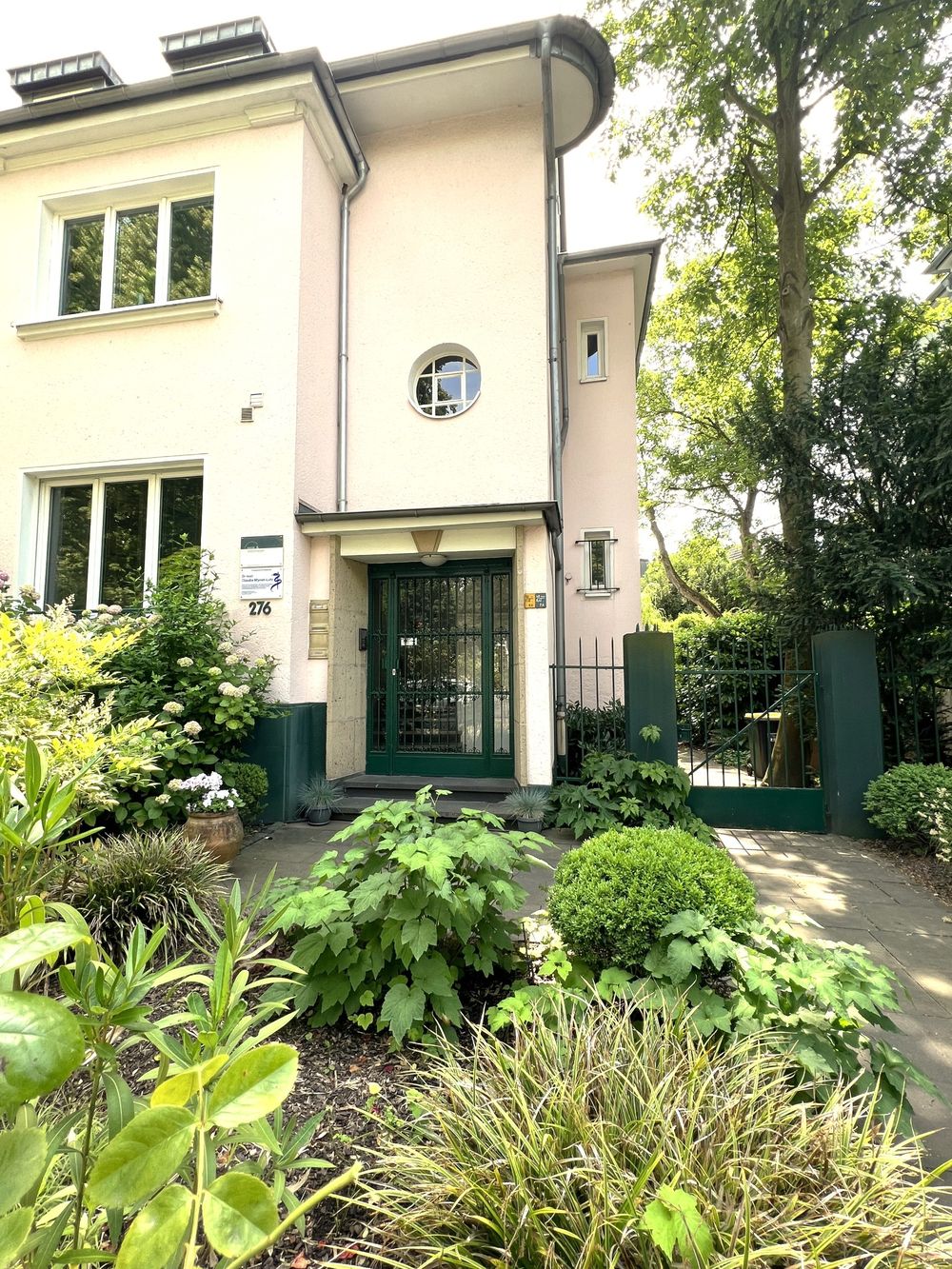 Hauseingang der Praxis in der Dürener Straße 276 mit grünem Vorgarten